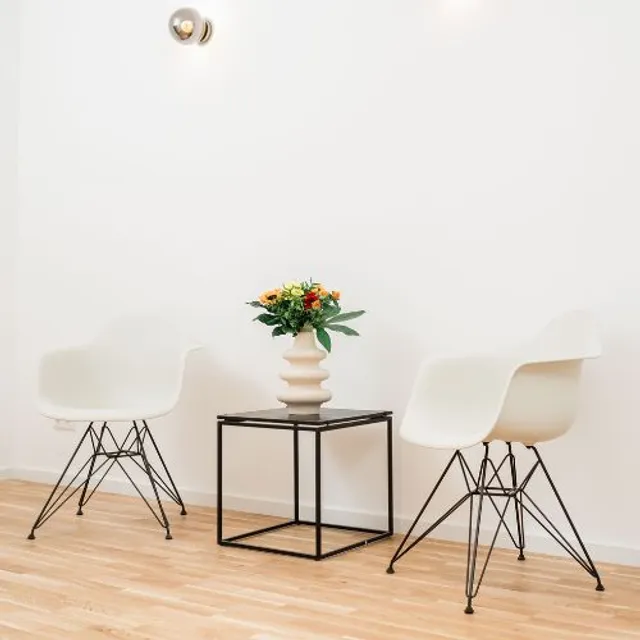 Zwei weiße Schalensessel mit Beistelltisch und Blumenstrauß im Wartebereich