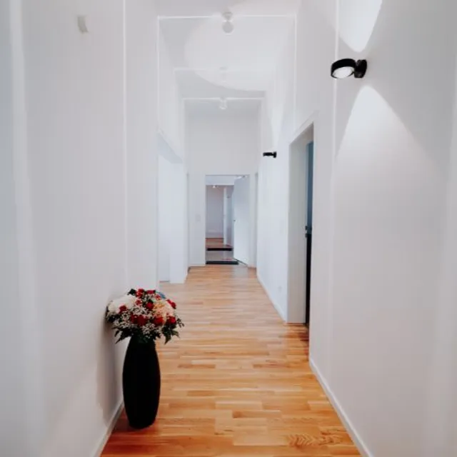 Heller Flur der Praxis mit Holzboden und einem Blumenstrauß